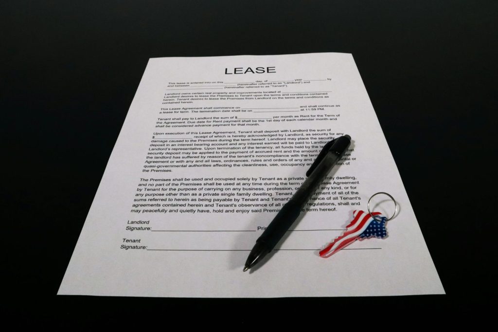 Lease agreement document with pen and American flag keychain on black desk