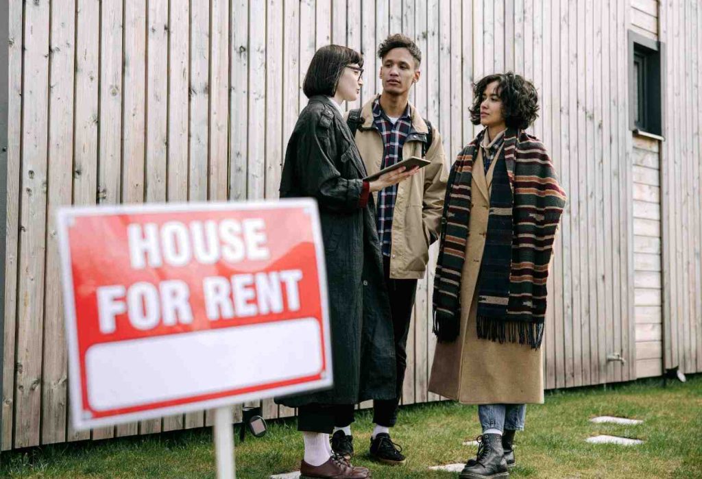 House for rent sign as a landlord tours a couple through a rental home, illustrating subletting vs subleasing options for prospective tenants.