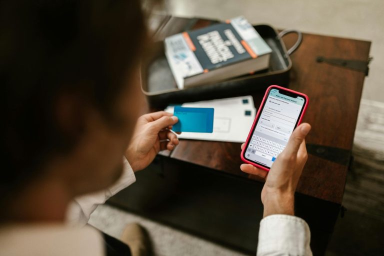 Person holding a credit card and entering payment details on a smartphone, managing online banking and checking for hidden bank fees