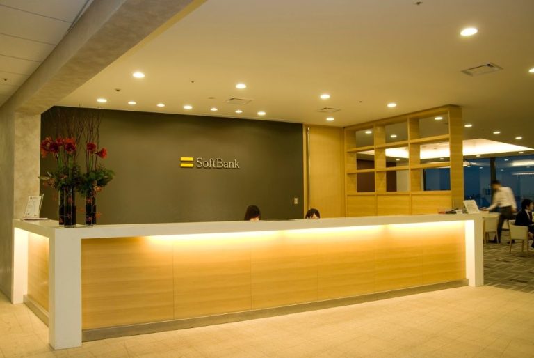 SoftBank corporate office reception area with modern front desk, company logo on wall, and warm lighting.