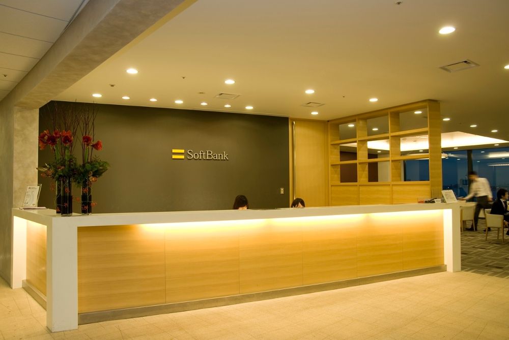 SoftBank corporate office reception area with modern front desk, company logo on wall, and warm lighting.