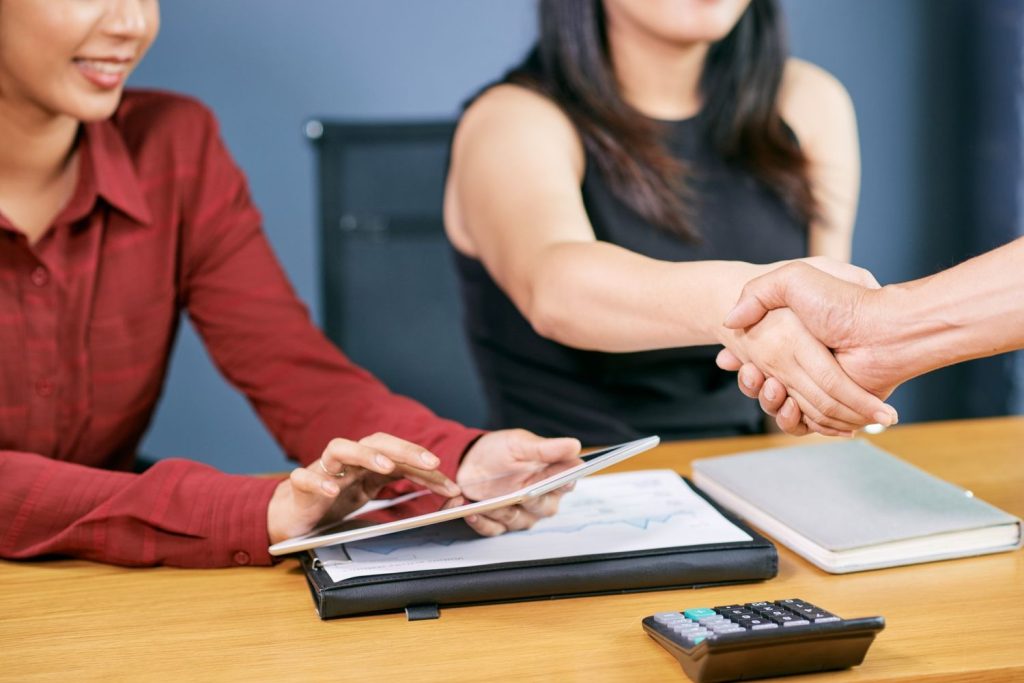 Professionals shaking hands after a deal, likely discussing the final interest rate for a loan.