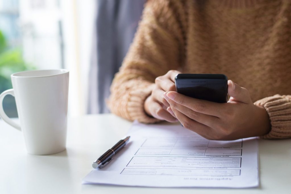 A person checking their phone to compare the APR on a financial application form.