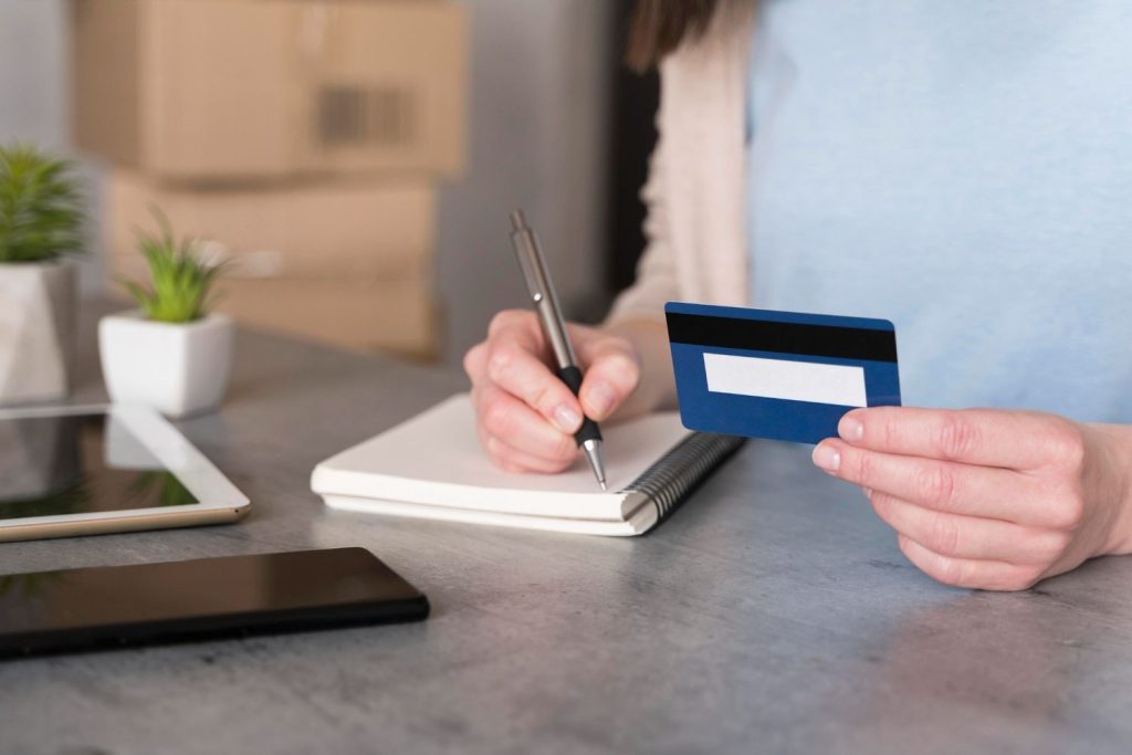 A consumer holding a credit card while noting down the interest rate for her records.