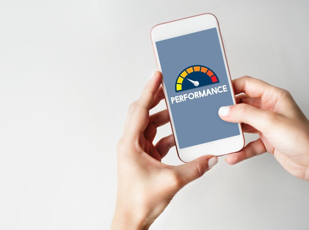 Two hands holding a phone with a gauge meter that shows a poor to goodr scale for credit score