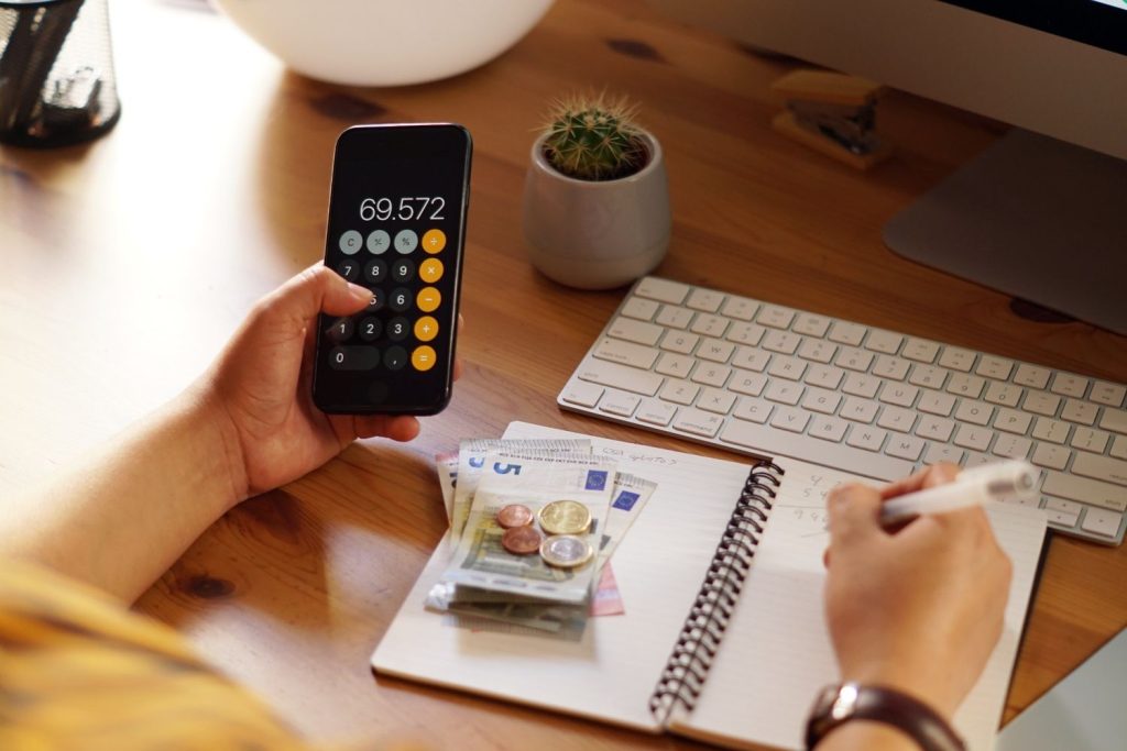 Person holding a smartphone while calculating their debt-to-income ratio.