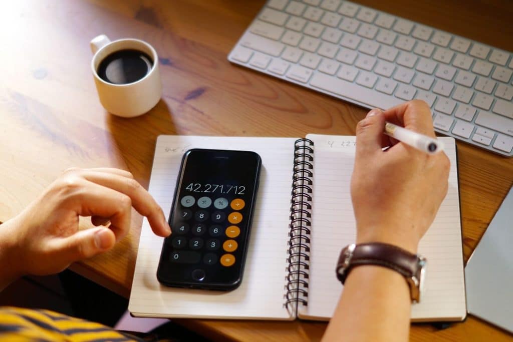 Close-up of a person using a smartphone calculator and notebook to plan for unsecured loans.