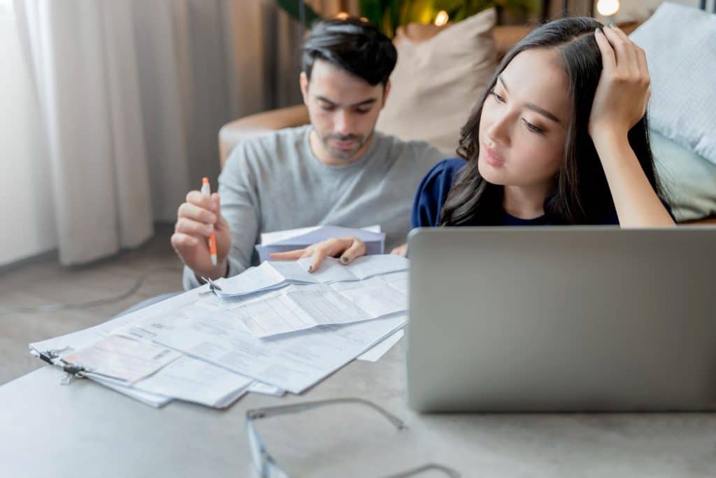 A stressed couple reviewing multiple bills and paperwork, considering personal loans for debt consolidation.