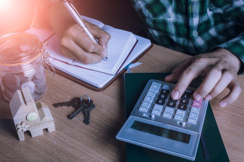 Person using calculator and writing on paper.