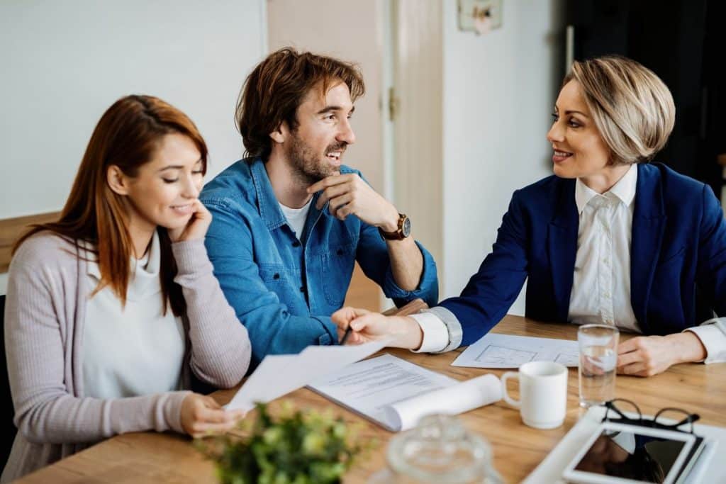 A happy couple discussing the terms of unsecured loans with a professional financial advisor.