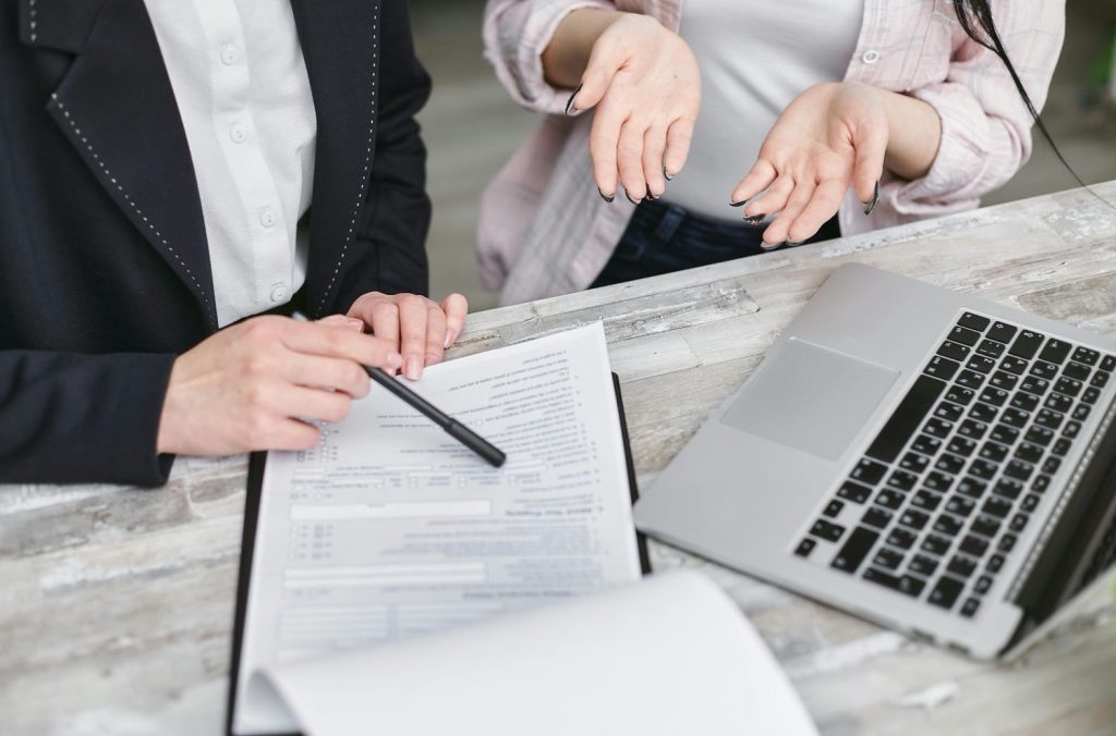 A lender pointing to terms on a document during an FHA vs conventional loan comparison meeting with a client.
