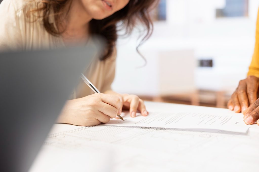 A grantee signs a real estate contract during a grantor vs grantee property transfer meeting.