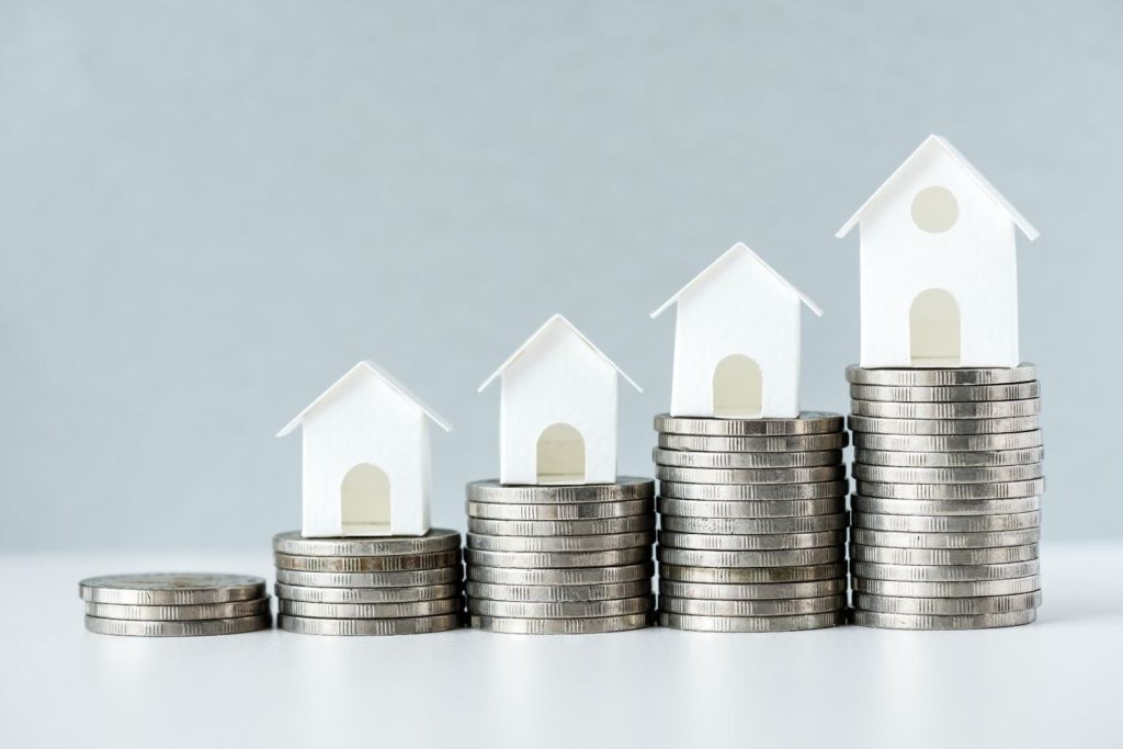 A visual of increasing coin stacks with model houses representing growing home equity for a reverse mortgage.