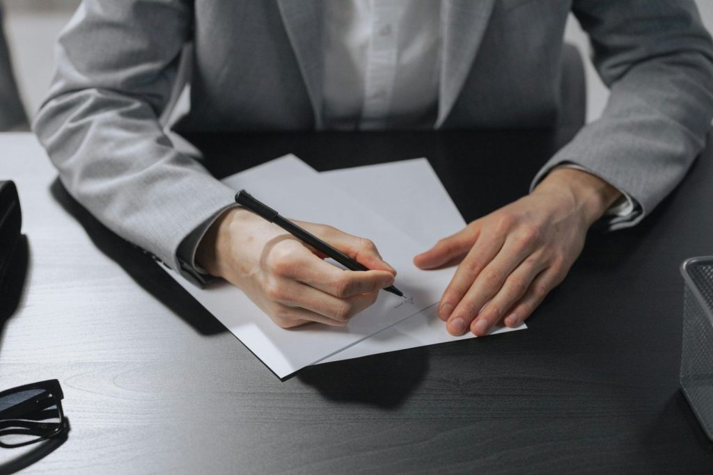 Professional signing a debt validation letter at a desk with documents and a pen.