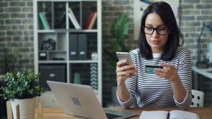 Woman reviewing her credit card and phone to check for charges before filing a chargeback.