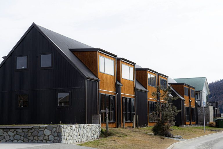 Contemporary black and wood townhouses with steep gabled roofs.
