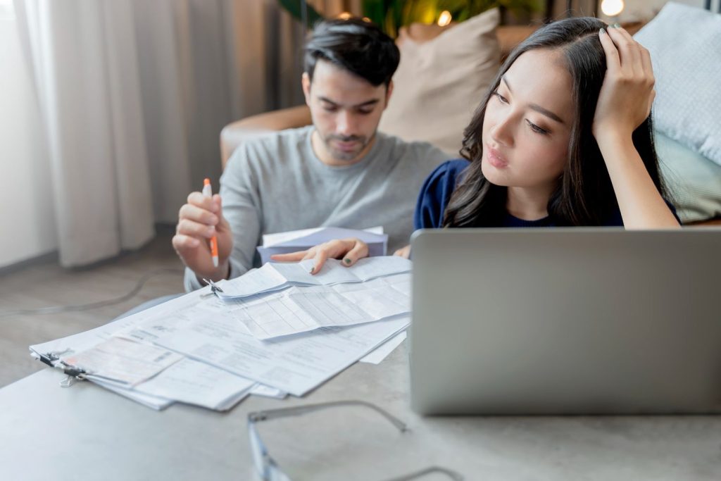 A stressed couple reviewing bills, searching for tips on how to reduce electricity bill at home.