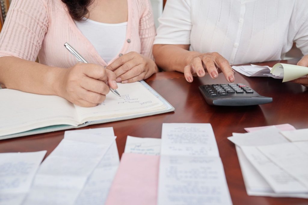 People reviewing receipts, using a calculator, and recording expenses while calculating FICA tax obligations.