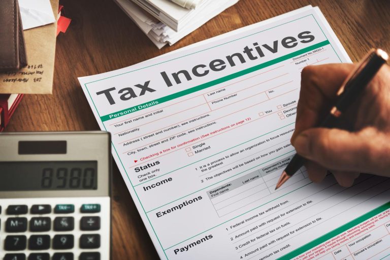 Person completing a tax form beside a calculator while reviewing FICA tax calculations and records.