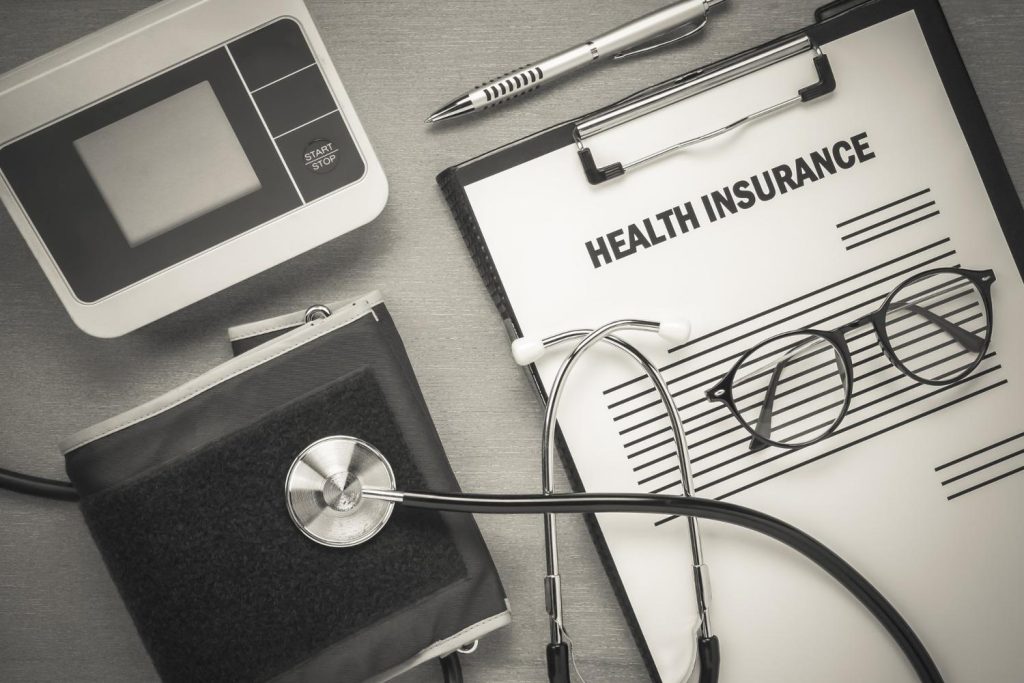 Alt text: Health insurance form with stethoscope and blood pressure monitor illustrating differences between HDHP and PPO plans.