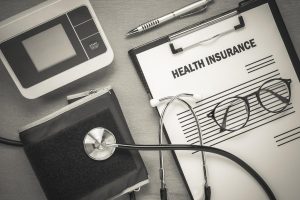 Alt text: Health insurance form with stethoscope and blood pressure monitor illustrating differences between HDHP and PPO plans.