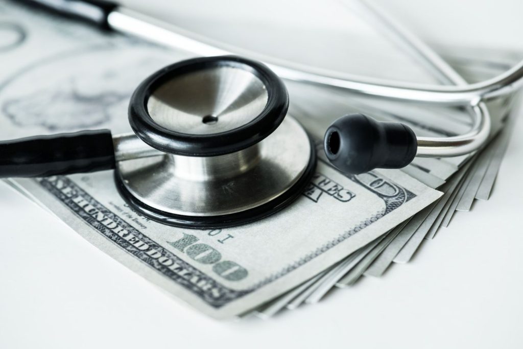 Stethoscope on cash illustrating healthcare costs and expenses related to Medicaid and Medicare coverage.