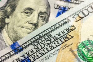 Close-up of U.S. $100 bills featuring Benjamin Franklin, illustrating inflation and changes in purchasing power.