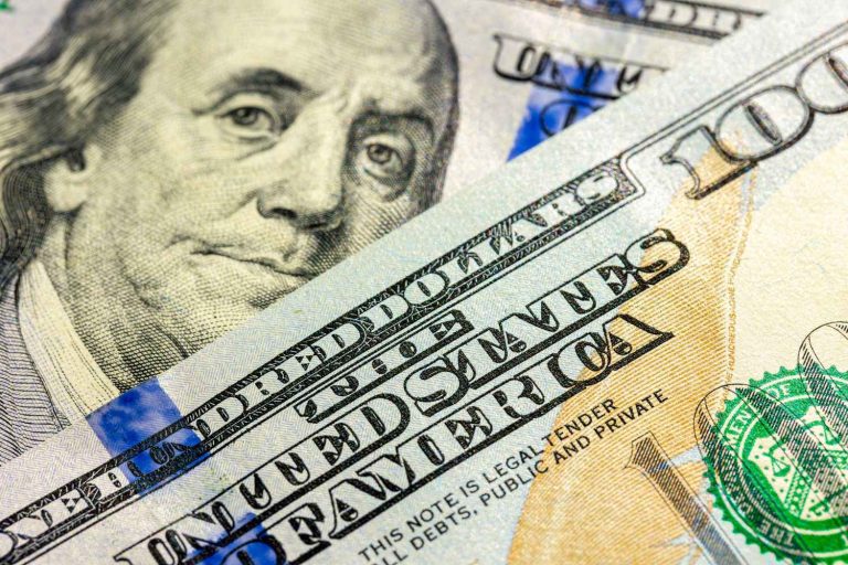 Close-up of U.S. $100 bills featuring Benjamin Franklin, illustrating inflation and changes in purchasing power.