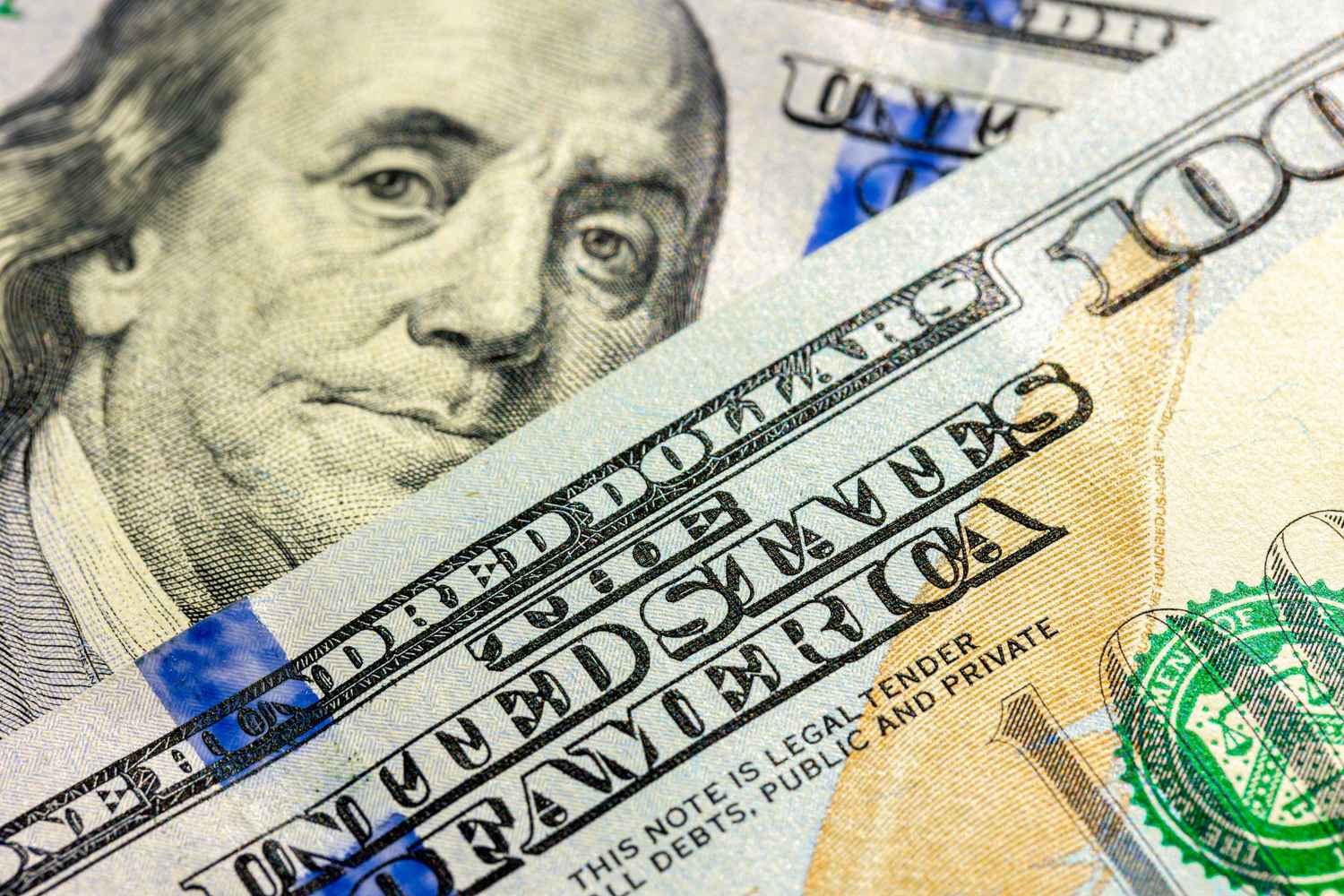 Close-up of U.S. $100 bills featuring Benjamin Franklin, illustrating inflation and changes in purchasing power.
