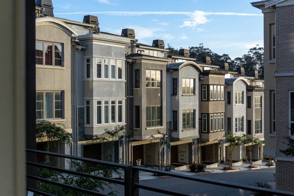 Modern gray stucco townhouses viewed from balcony at dusk.