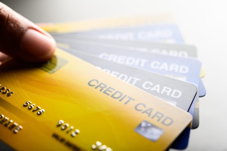 Hand holding several credit cards fanned out against a light background.
