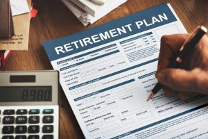 Retirement plan form with calculator and paperwork showing 403b and 401k retirement planning decisions.