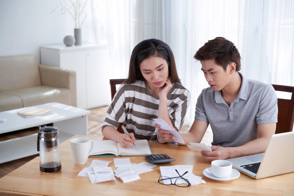 Couple reviewing bills and expenses at home while comparing 403b and 401k retirement savings options.