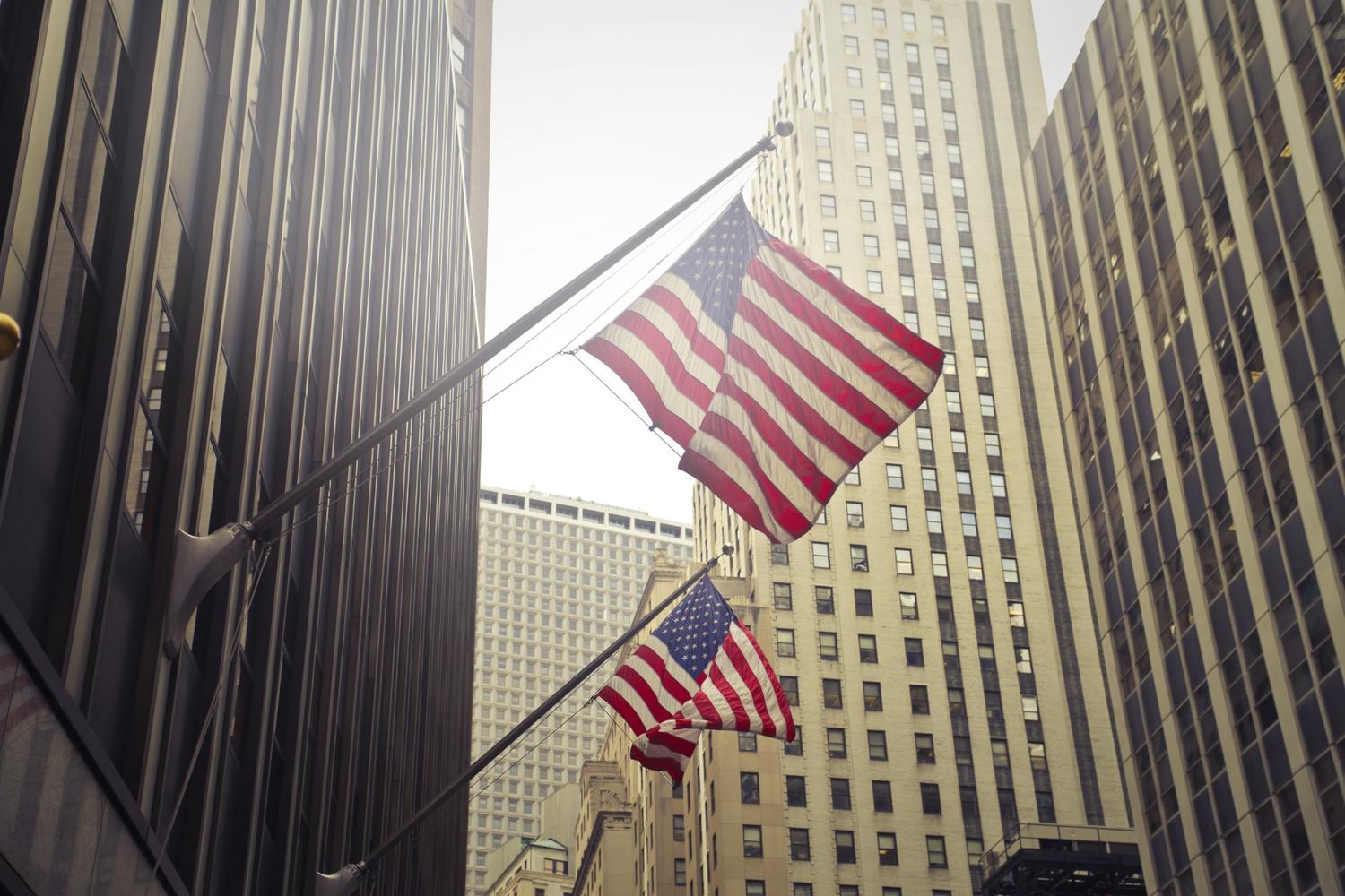 Shot of two American or us flags on a high rise building.
