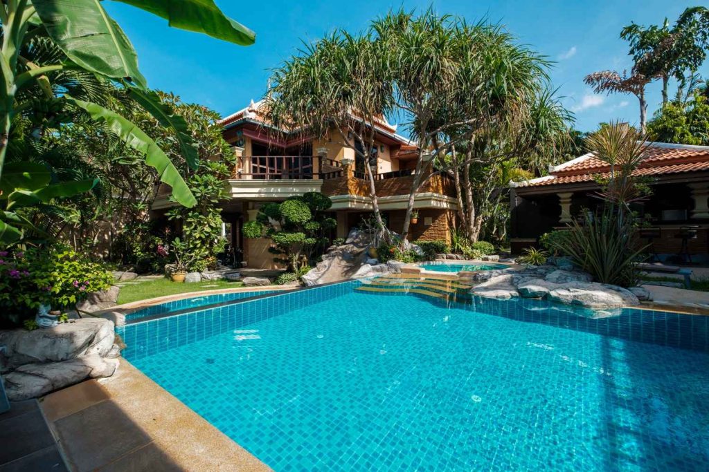 Luxury timeshare property with a large swimming pool, tropical landscaping, and resort-style villa under a clear sky.