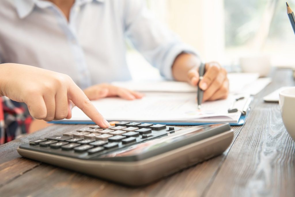 Person using a calculator while reviewing paperwork to estimate federal tax brackets and taxable income.