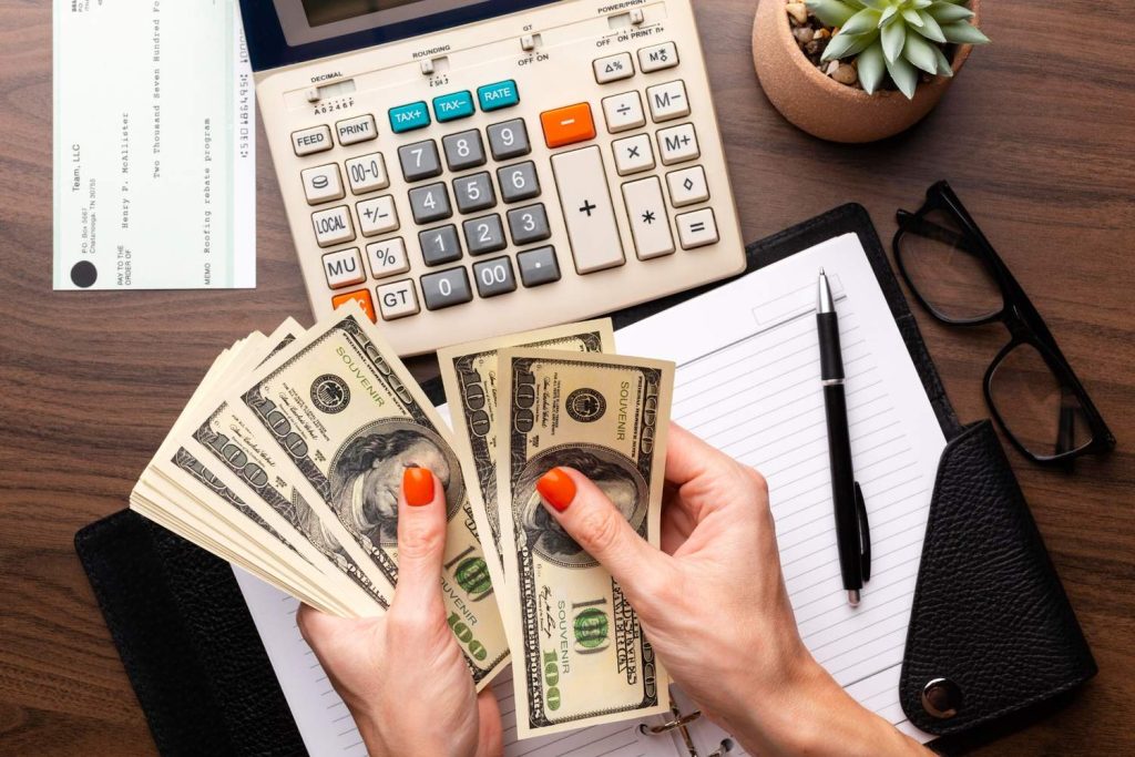 Counting cash beside a calculator and checkbook while comparing payday loan alternatives for short-term expenses.