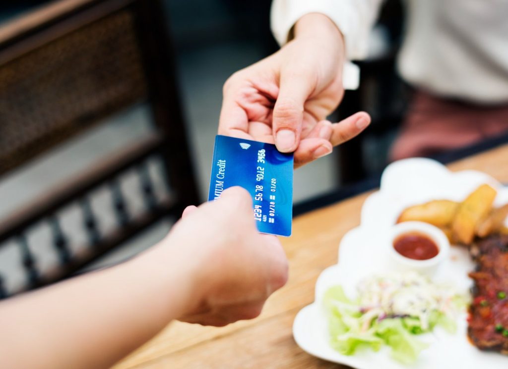 Customer paying with a credit card at a restaurant, showing debt consolidation loan vs balance transfer in practice.
