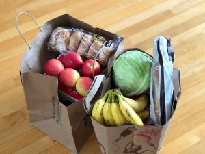 Paper grocery bags filled with produce and bread, highlighting rising grocery prices for everyday household shopping.