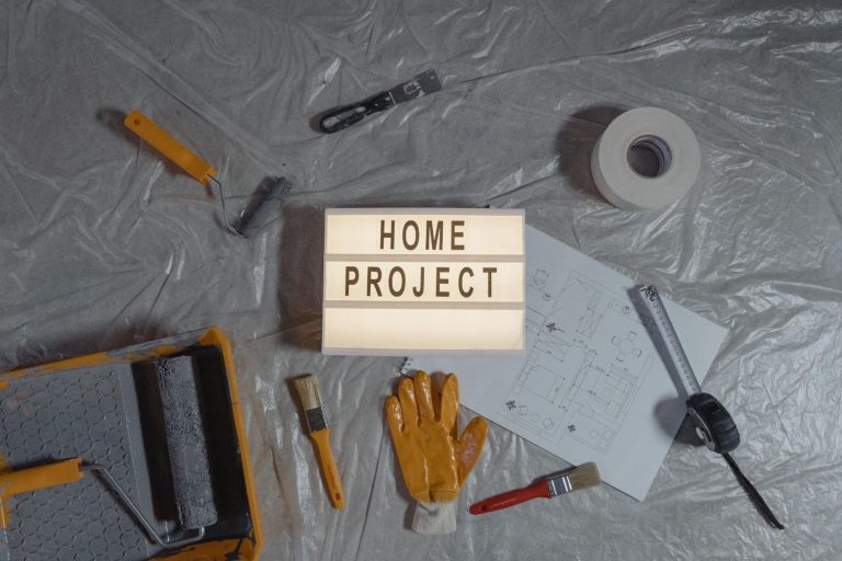 Home project plans, paint tools, gloves, and measuring tape arranged for a renovation project.