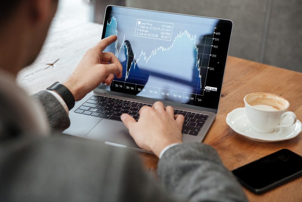 Investor reviews stock charts on a laptop while researching an index fund for long-term portfolio growth.