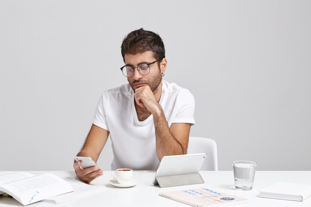 Person checking finances on a smartphone while researching payday loans explained at a desk.