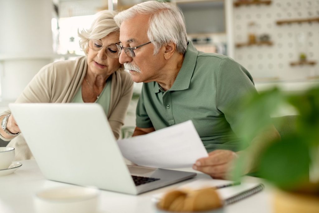 Couple reviewing finances on a laptop, comparing roth IRA vs traditional IRA for retirement planning.