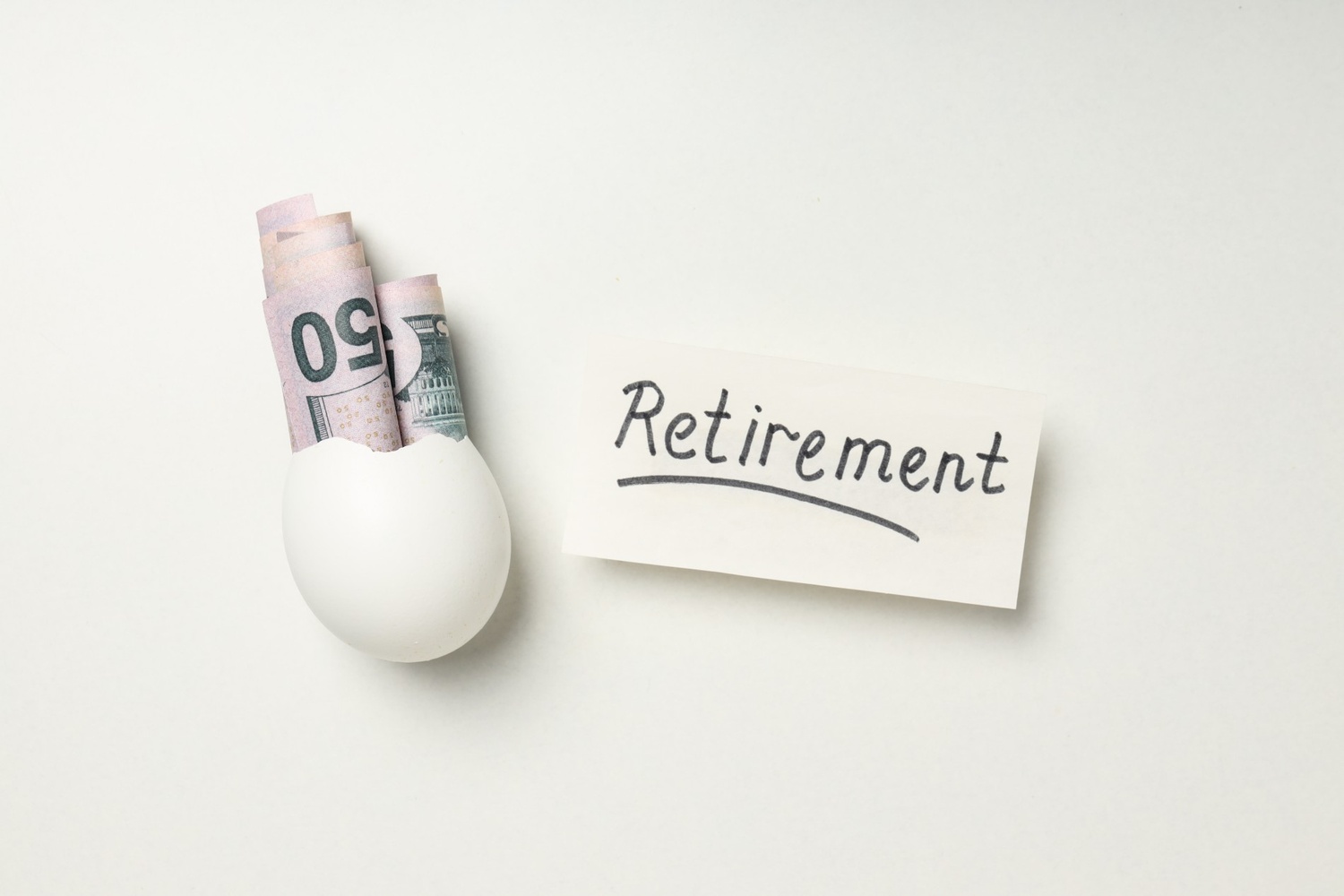 Eggshell holding cash beside a retirement note, illustrating roth IRA vs traditional IRA savings strategies.