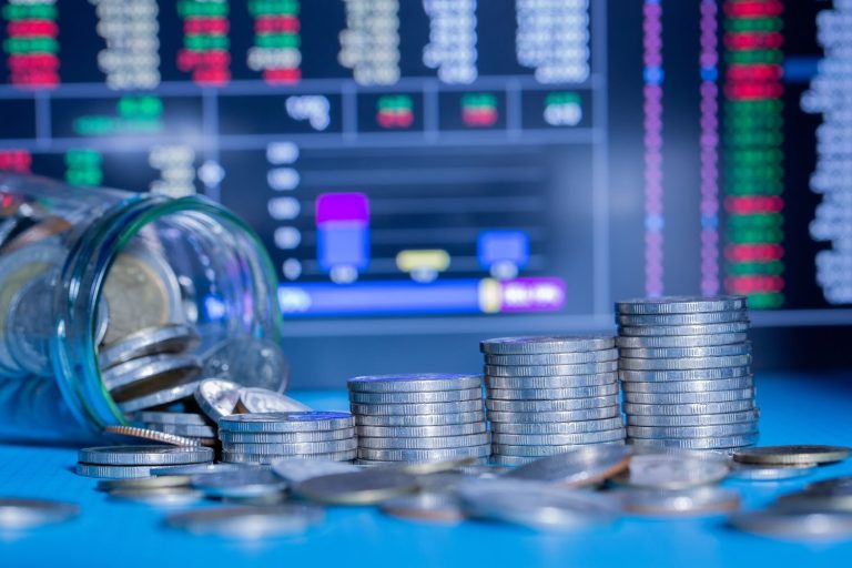 Coins stacked beside a market chart illustrate how an index fund can grow through long-term investing.