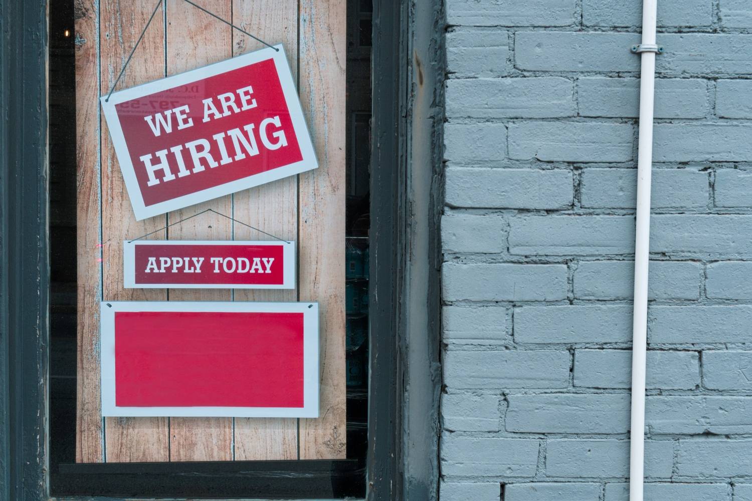 Storefront hiring sign illustrates rising jobless claims and changing employment opportunities in the local job market.