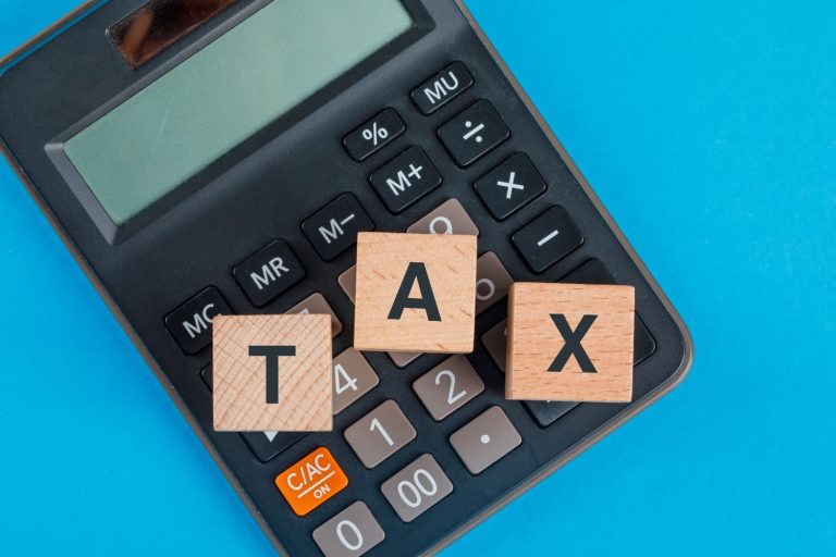 Calculator with wooden TAX blocks illustrating federal tax brackets and income tax calculations.