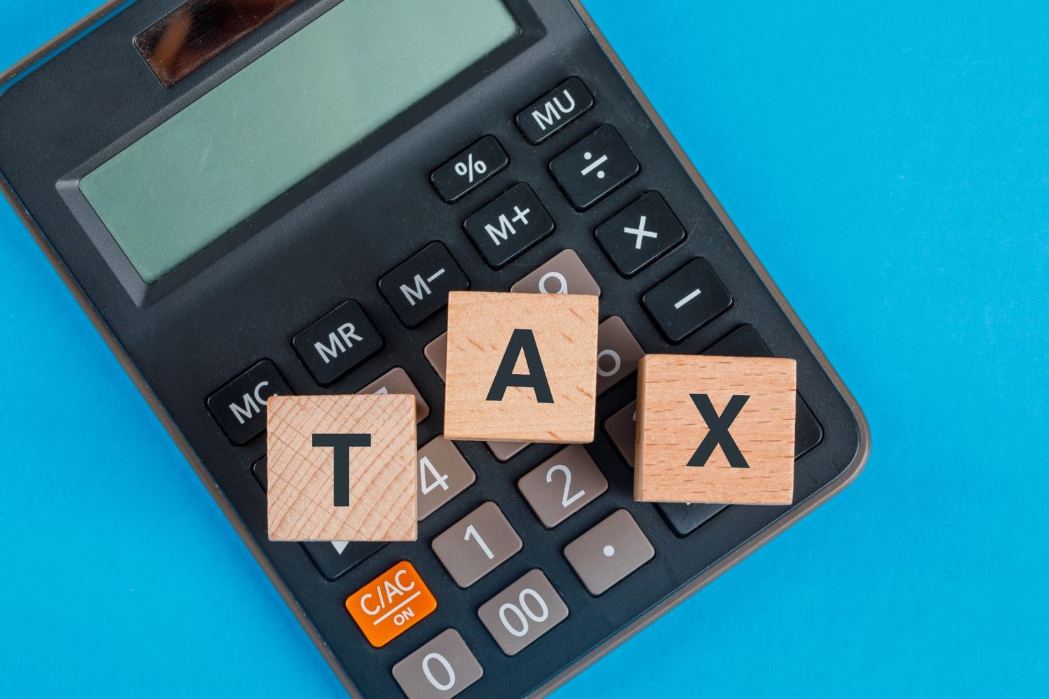 Calculator with wooden TAX blocks illustrating federal tax brackets and income tax calculations.