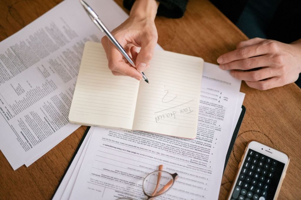 Person reviewing tax forms and notes while considering an offer in compromise for IRS tax debt relief.