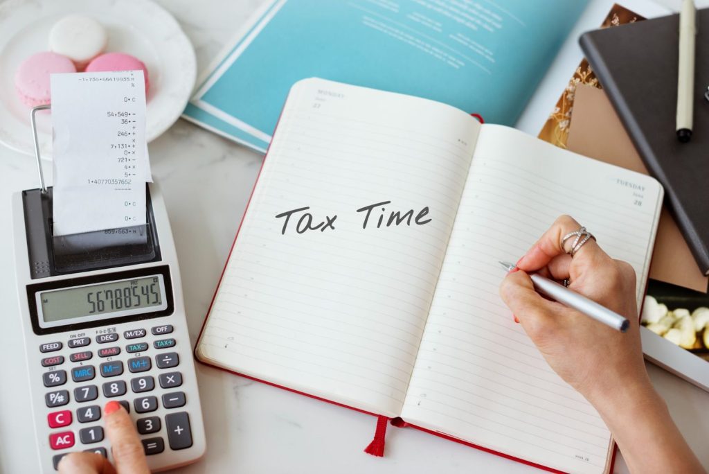 Person writing in a planner beside a calculator during federal tax brackets planning and tax preparation.